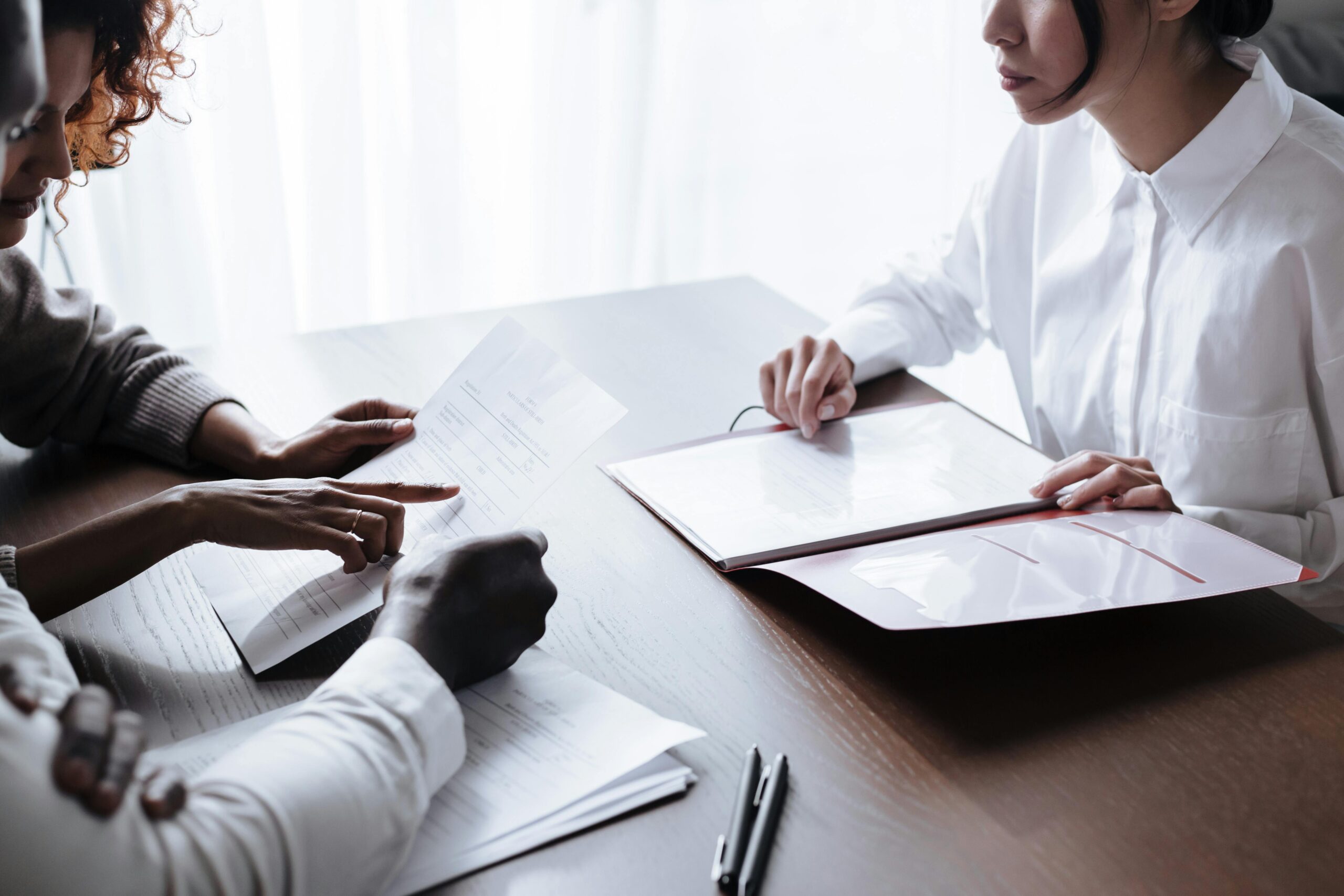 A diverse group of adults reviewing documents during a meeting at an office table.